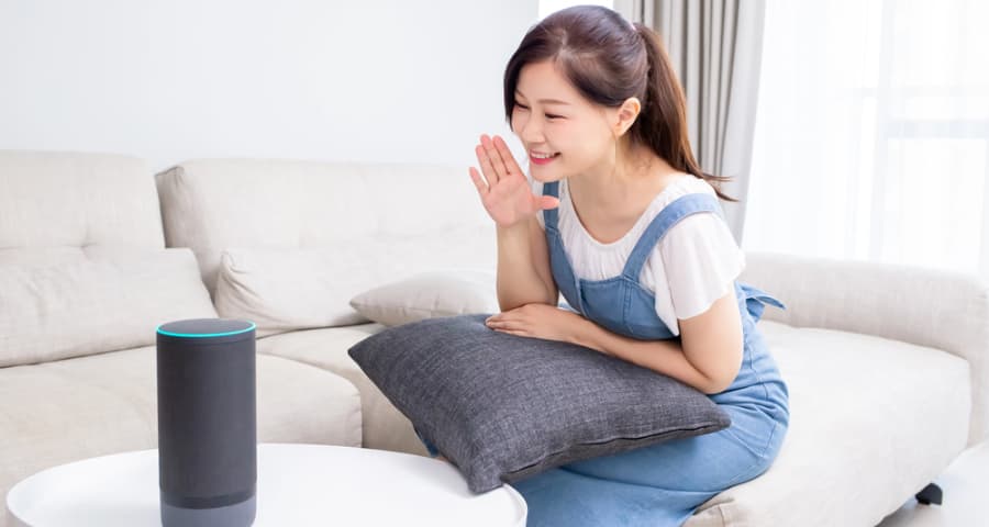 Young woman at home giving a command to a smart speaker